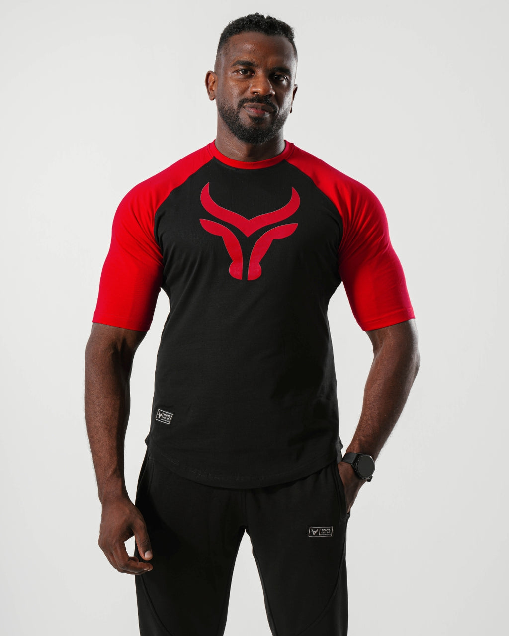 Man wearing a black and red sports outfit with a logo on a white background

