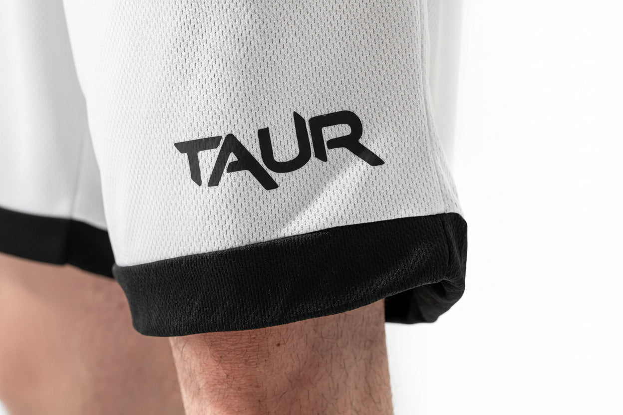 Close-up of a white sports jersey with black trim and 'TAUR' logo on a person wearing it.