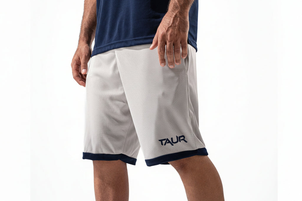 Person wearing white shorts with navy accents and 'TAUR' branding on a white background