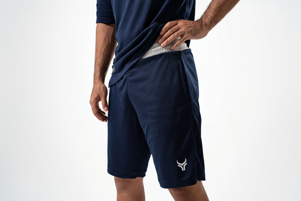 Person wearing navy athletic shorts with a logo on a white background