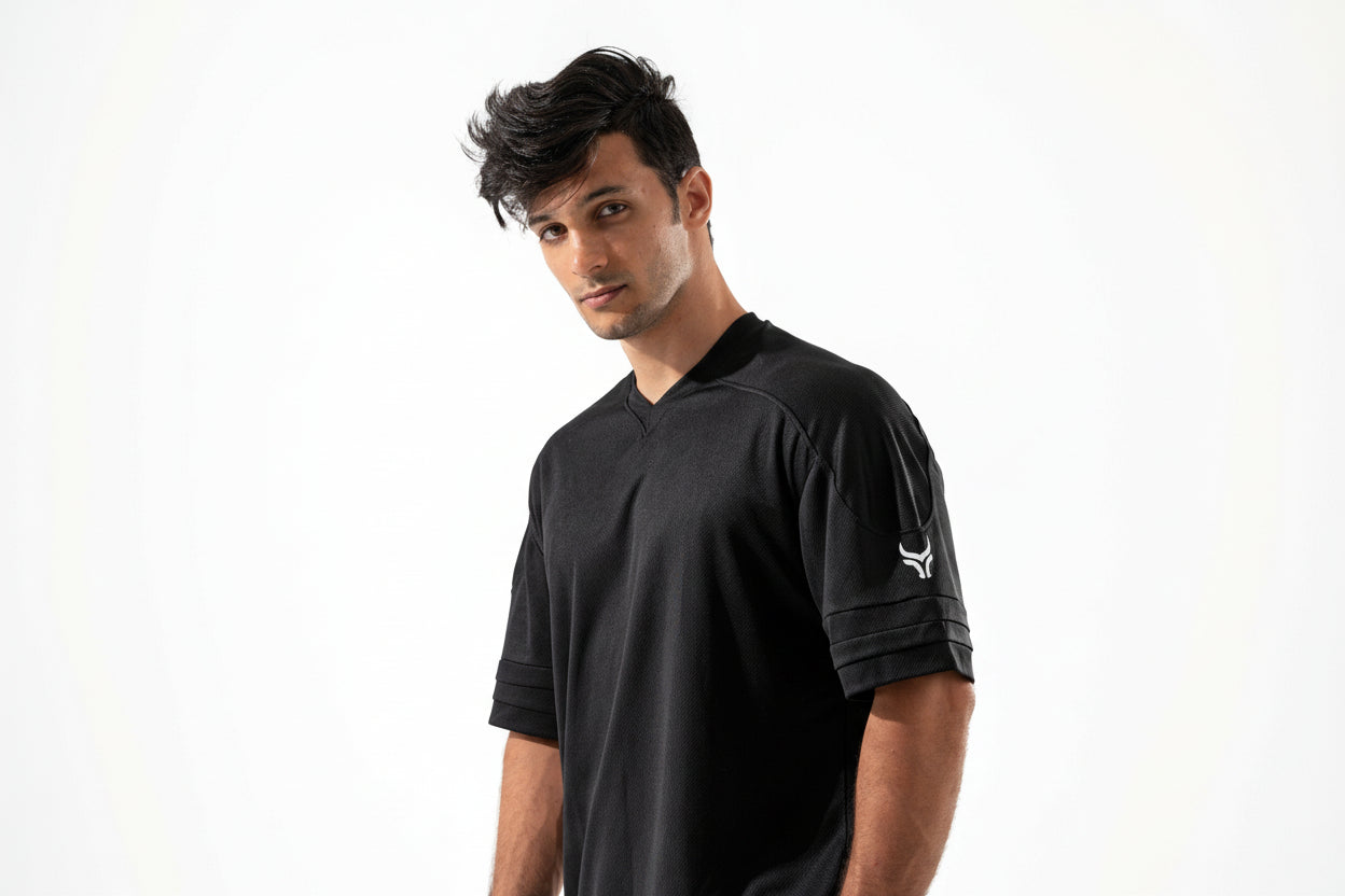 Man wearing a black polo shirt with a logo on a white background

