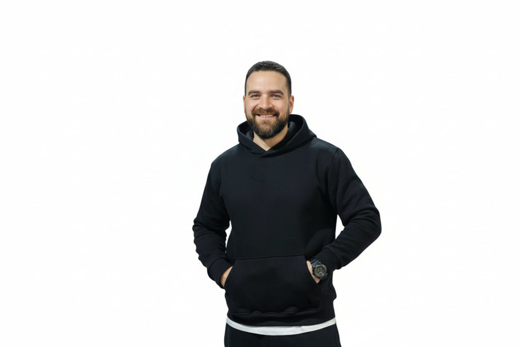 Man wearing a black hoodie standing in an indoor sports facility.

