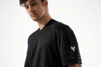 Man wearing a black t-shirt with a logo on the sleeve against a white background

