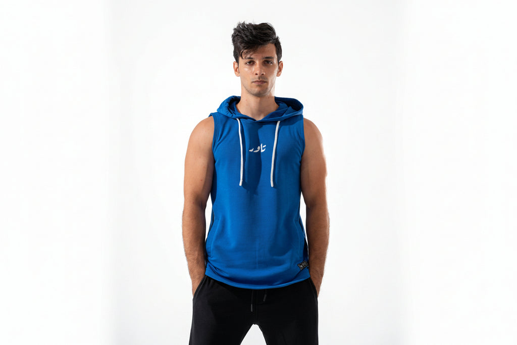 Man wearing a blue sleeveless hoodie with a white logo on a white background

