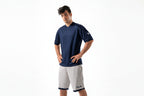 Man wearing a navy blue shirt and white shorts on a white background

