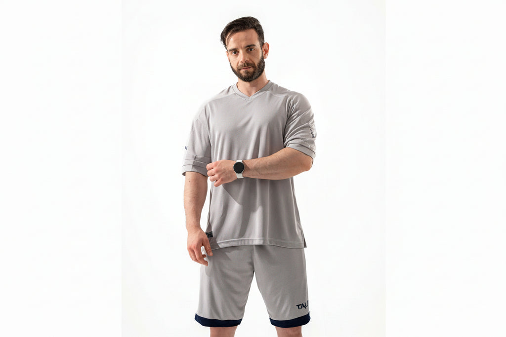 Man wearing a gray athletic outfit with a white background

