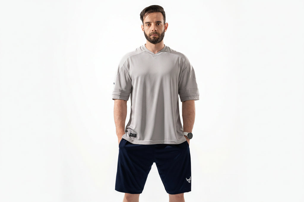 Man wearing a gray athletic shirt and navy shorts on a white background