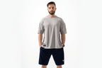 Man wearing a gray athletic shirt and navy shorts on a white background