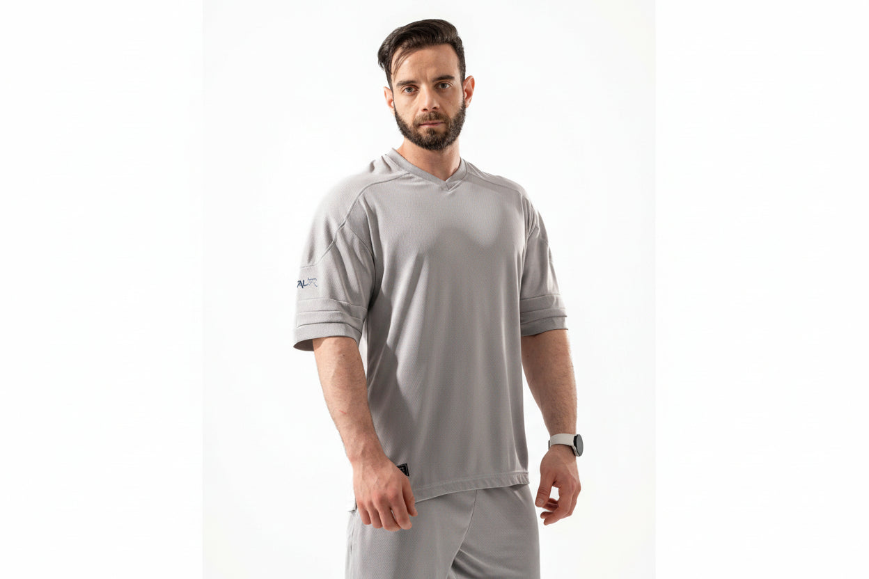 Man wearing a gray athletic outfit with a visible brand logo on a white background