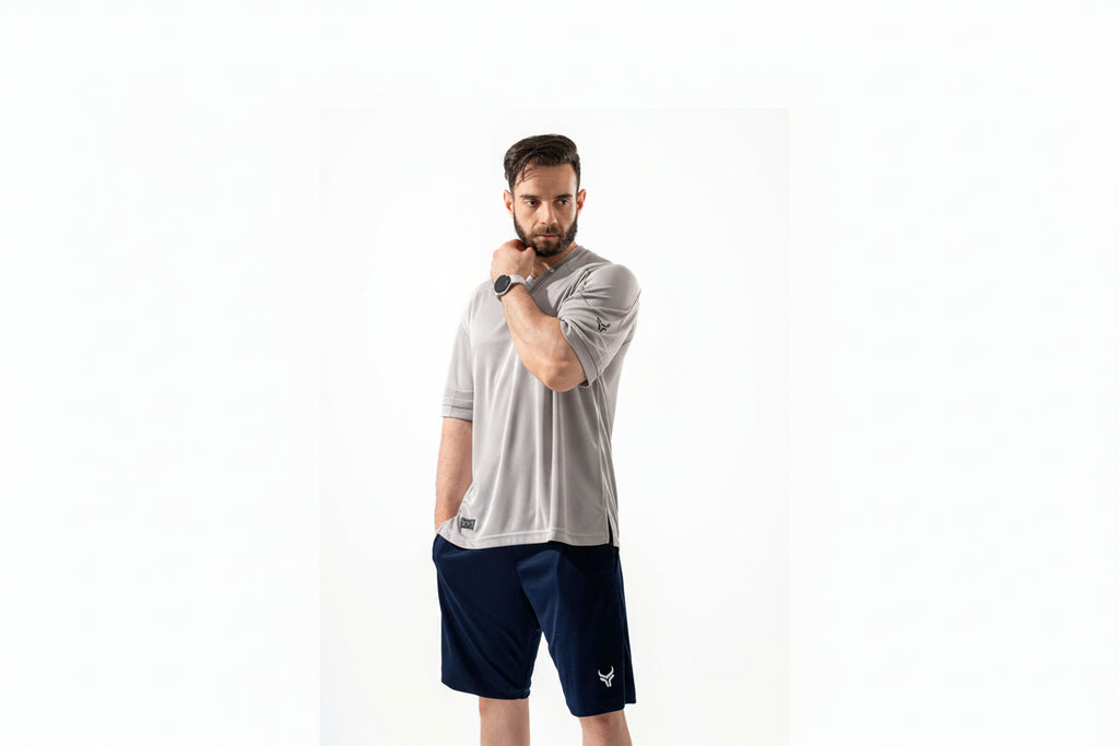 Man wearing a gray athletic shirt and navy shorts on a white background

