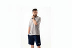 Man wearing a gray athletic shirt and navy shorts on a white background

