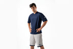 Man wearing a navy blue shirt and white shorts on a white background