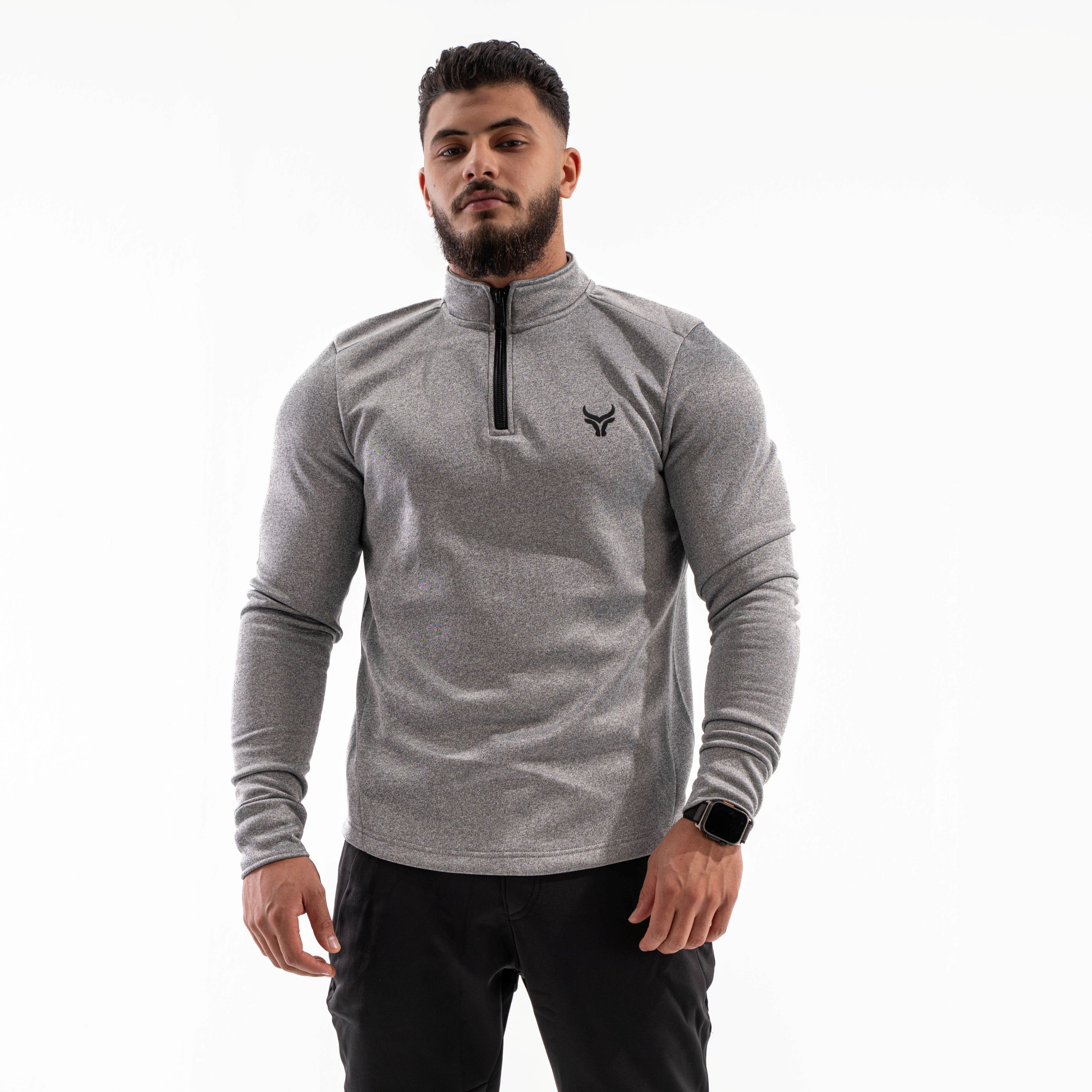 Man wearing a gray long-sleeve athletic shirt with a brand logo on a white background