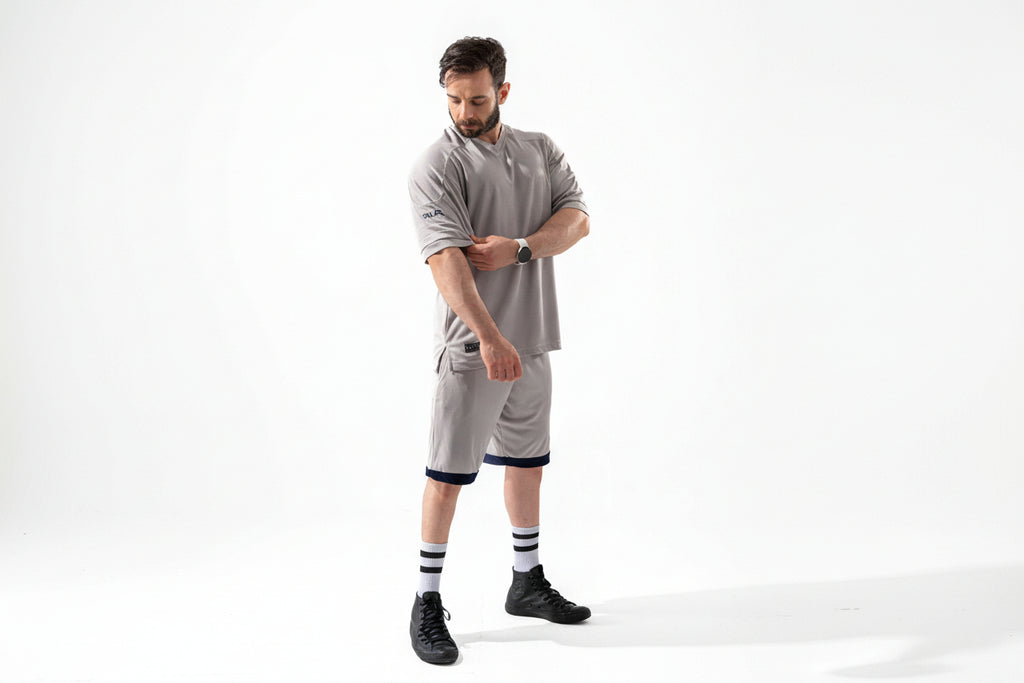 Man wearing a gray outfit with black shoes and socks on a white background