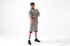 Man wearing a gray outfit with black shoes and socks on a white background