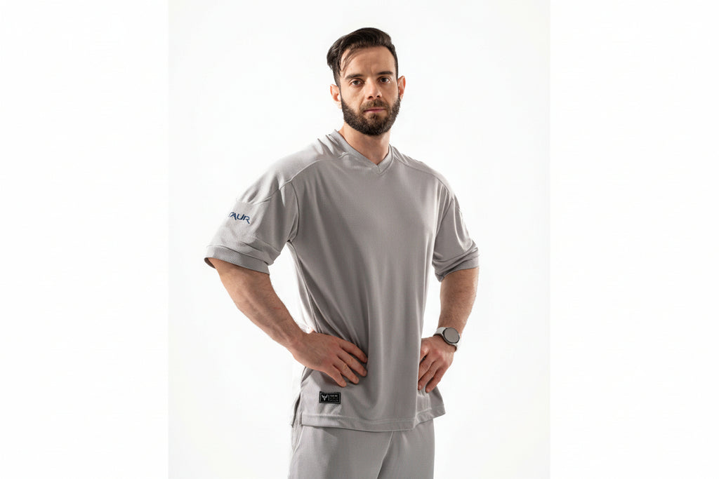 Man wearing a gray sports outfit with visible branding on a white background

