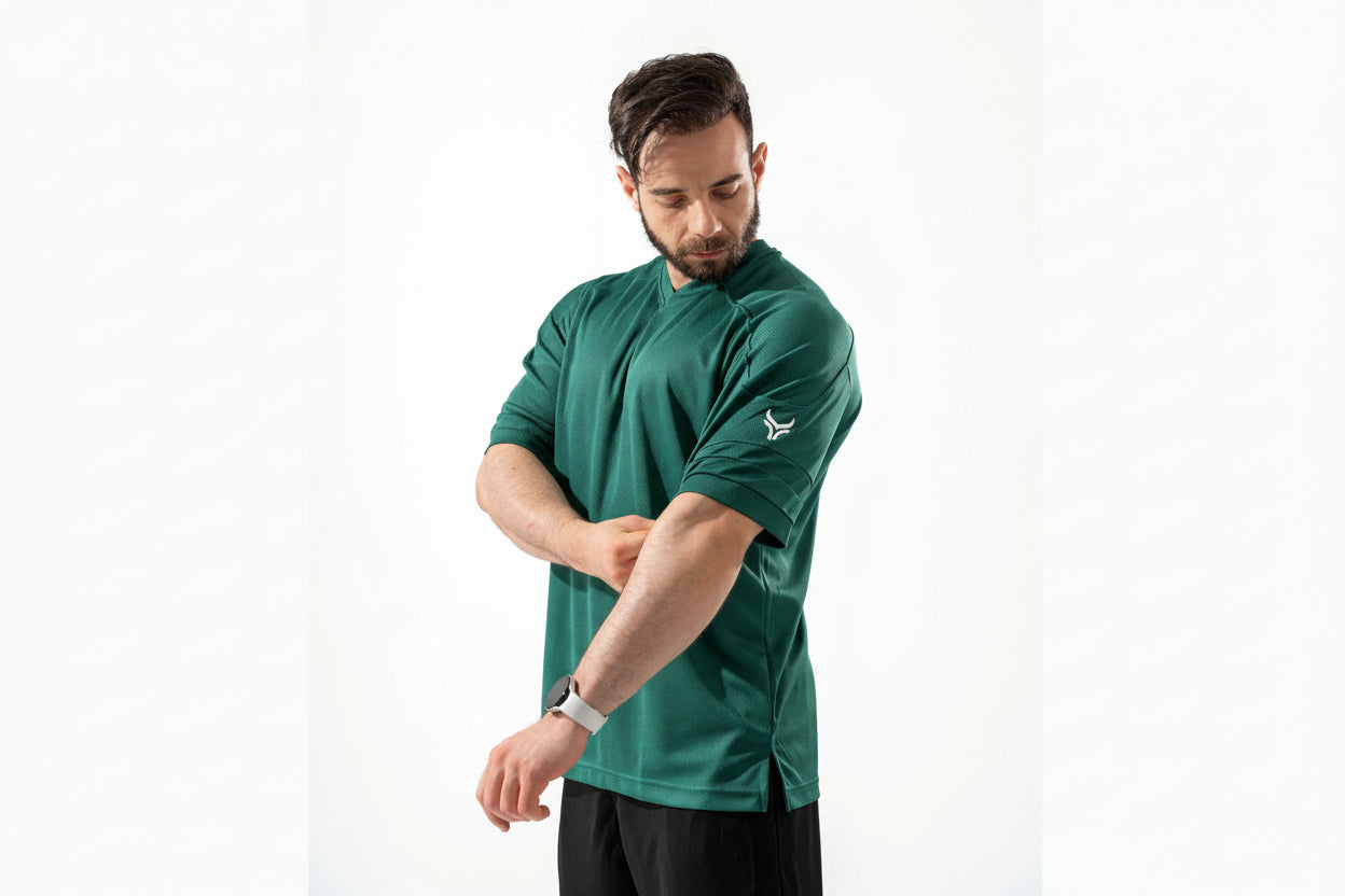 Man wearing a green athletic shirt with a logo on a white background

