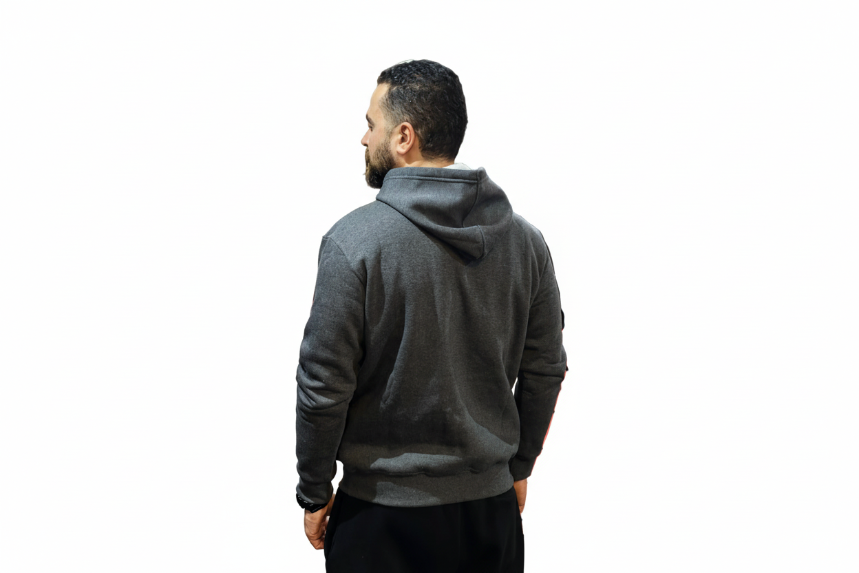 Person wearing a gray hoodie in a gym setting with punching bags and a cage.

