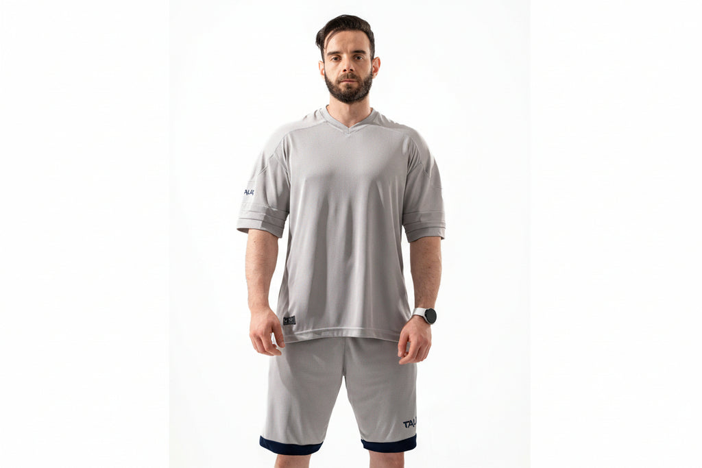 Man wearing a gray athletic outfit with a hood on a white background

