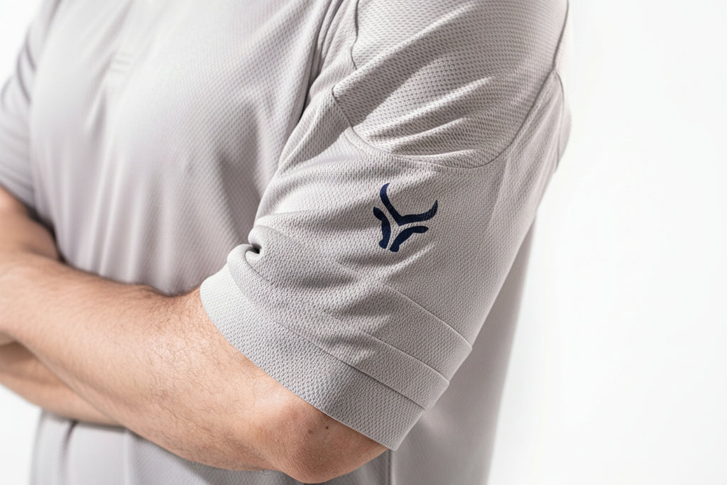 Close-up of a light gray polo shirt with a logo on the sleeve against a white background