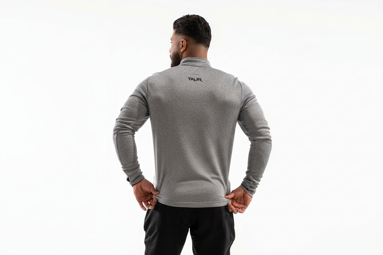 Man wearing a gray long-sleeve athletic shirt with a brand logo on the back, standing against a white background.