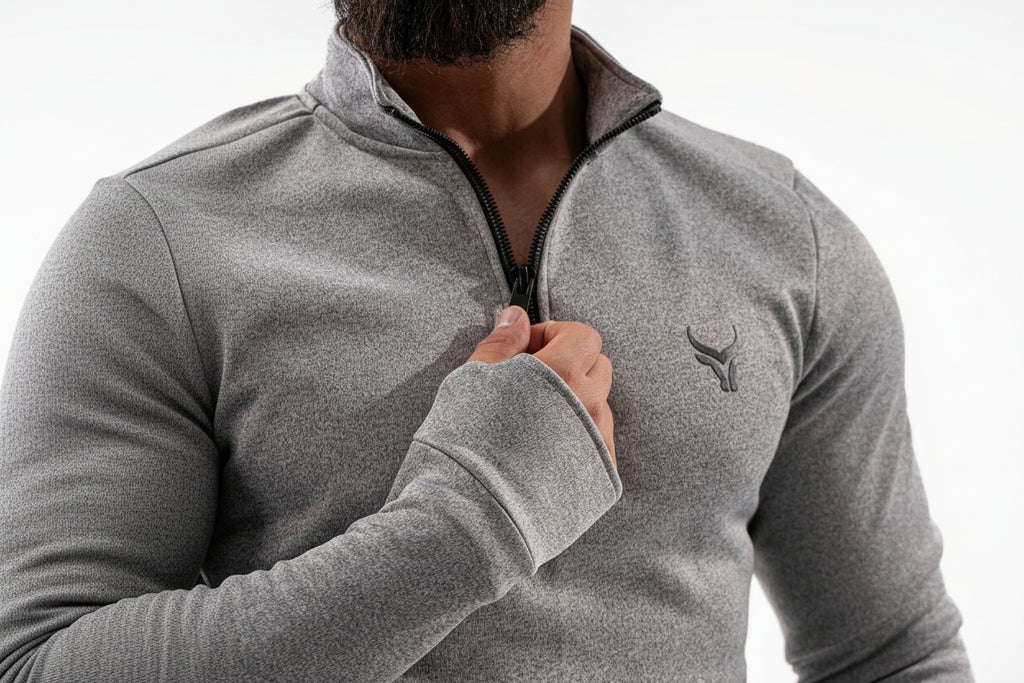 Person wearing a gray quarter-zip sweatshirt with a logo on a white background