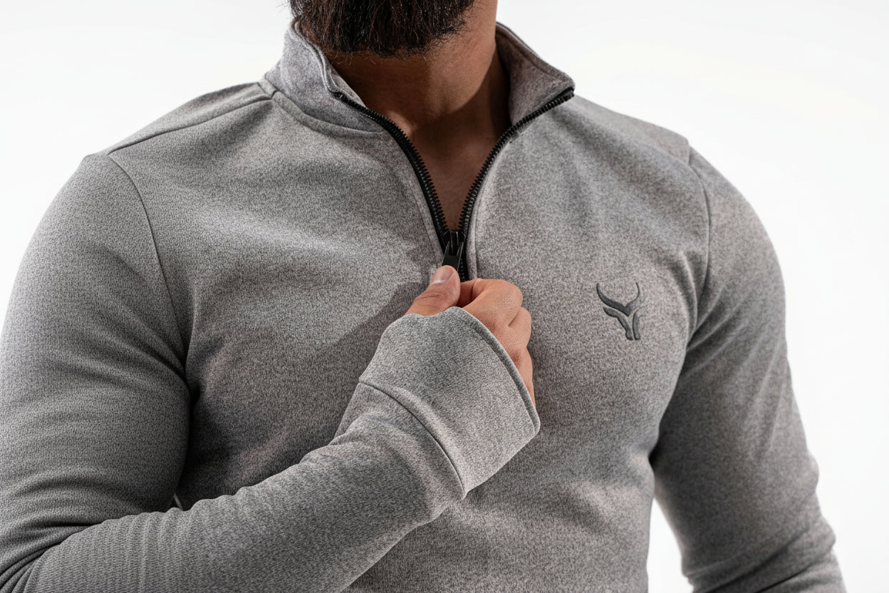 Person wearing a gray quarter-zip sweatshirt with a logo on a white background