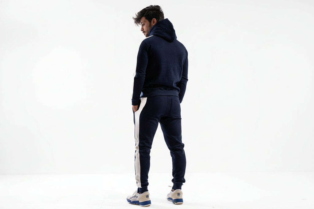Man wearing a navy tracksuit with white stripes on a white background

