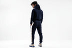 Man wearing a navy tracksuit with white stripes on a white background

