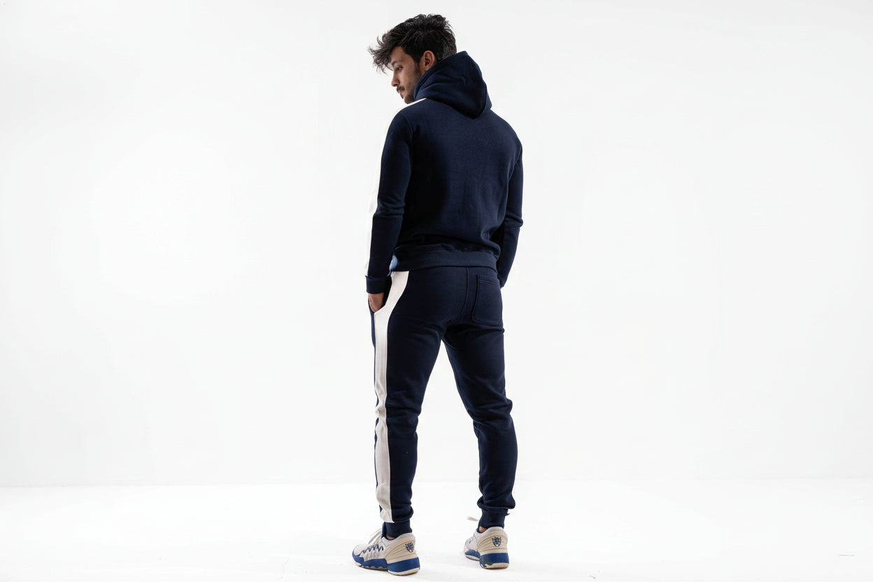 Man wearing a navy tracksuit with white stripes on a white background

