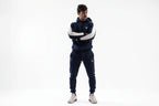 Man wearing a navy tracksuit with white sleeves on a white background

