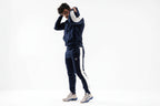 Person wearing a navy tracksuit with white stripes on a white background

