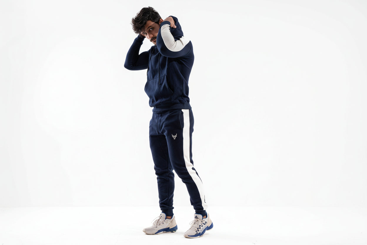 Person wearing a navy tracksuit with white stripes on a white background

