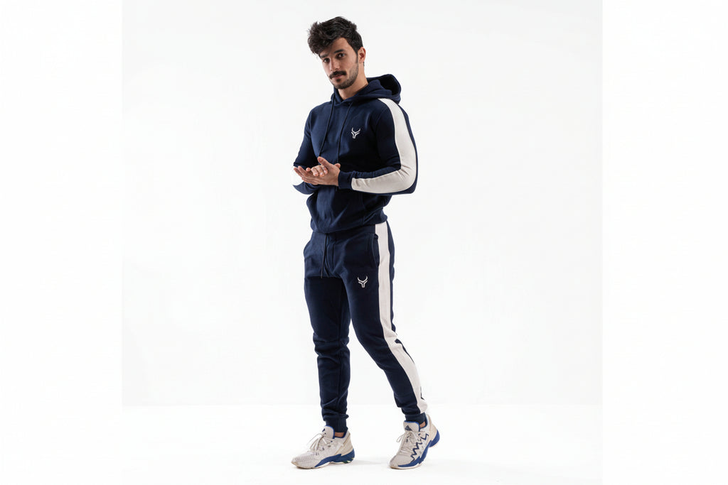 Man wearing a navy tracksuit with white accents on a white background

