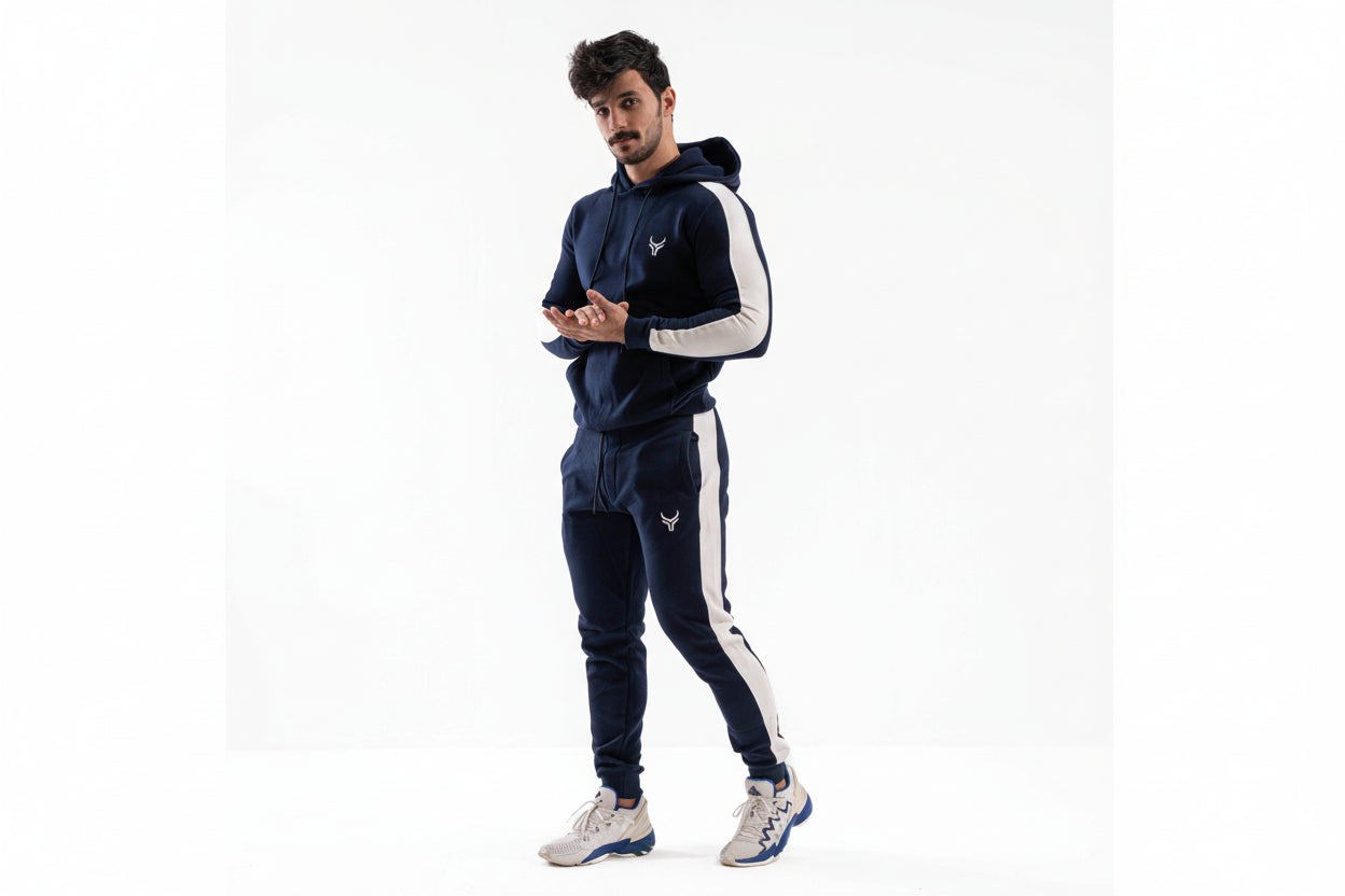 Man wearing a navy tracksuit with white accents on a white background


