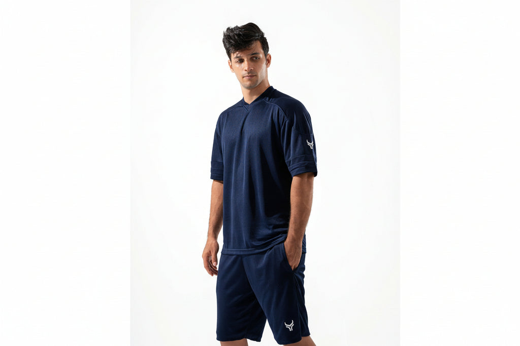 Man wearing a navy blue athletic outfit with a logo on a white background