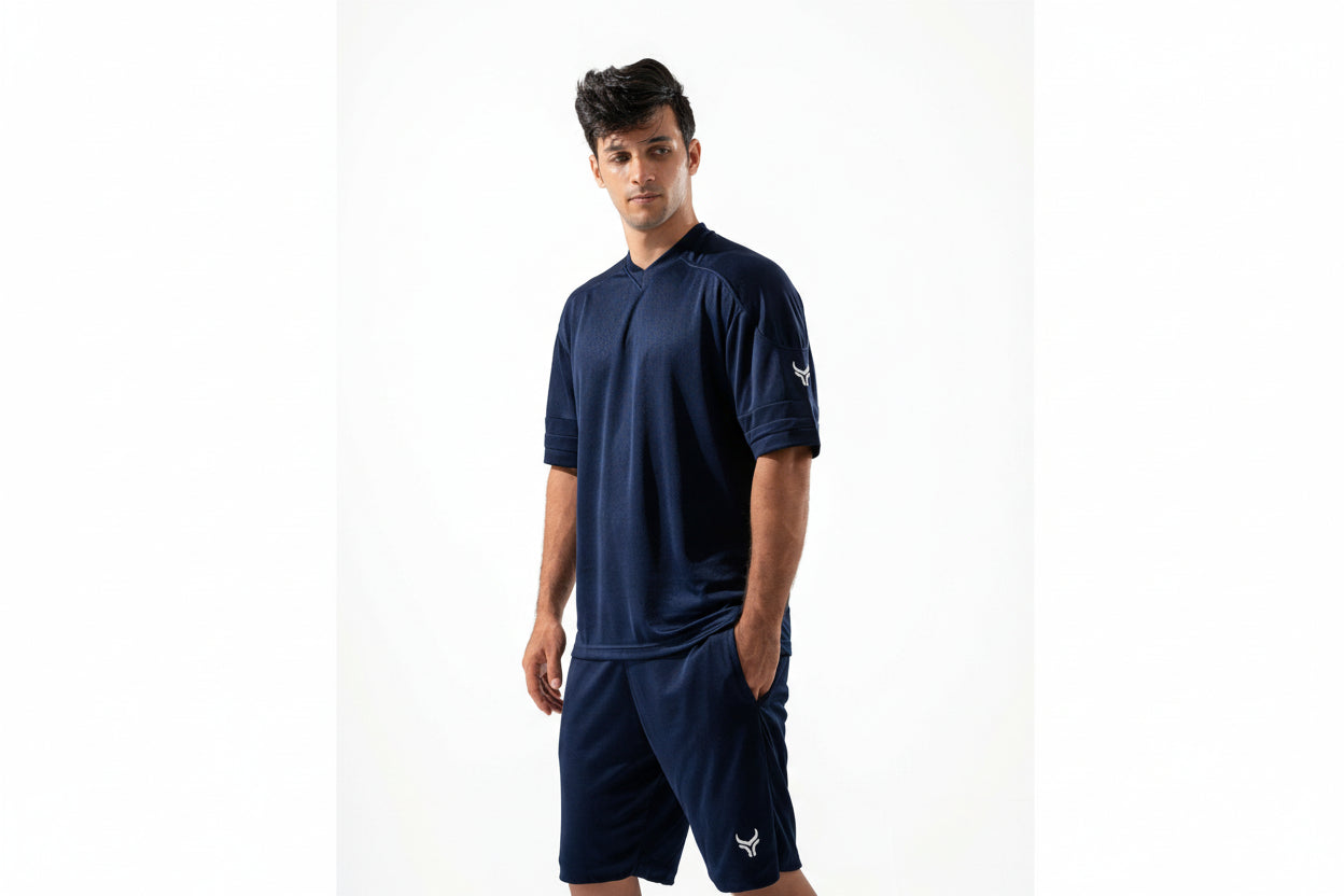 Man wearing a navy blue athletic outfit with a logo on a white background