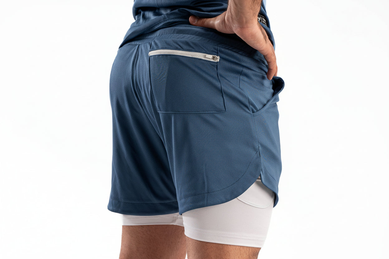 Person wearing a blue athletic shorts with a white inner layer on a white background

