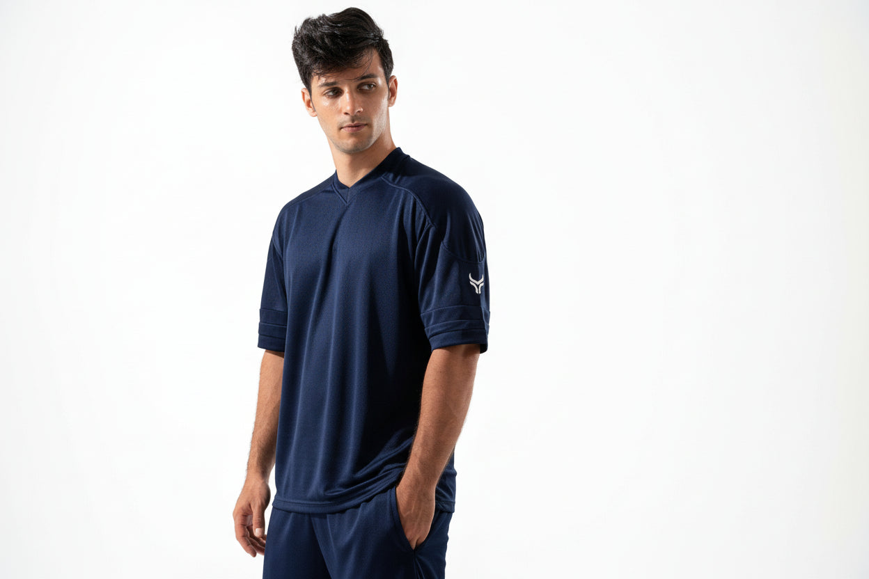 Man wearing a navy blue athletic outfit with a logo on a white background