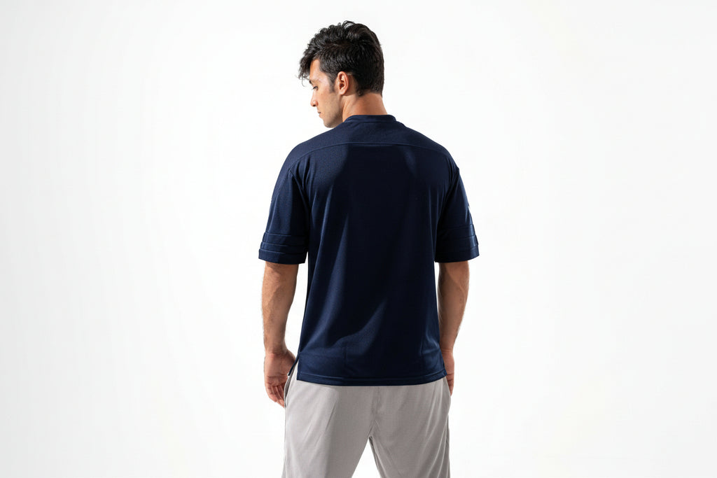 Man wearing a navy blue shirt and light gray shorts on a white background