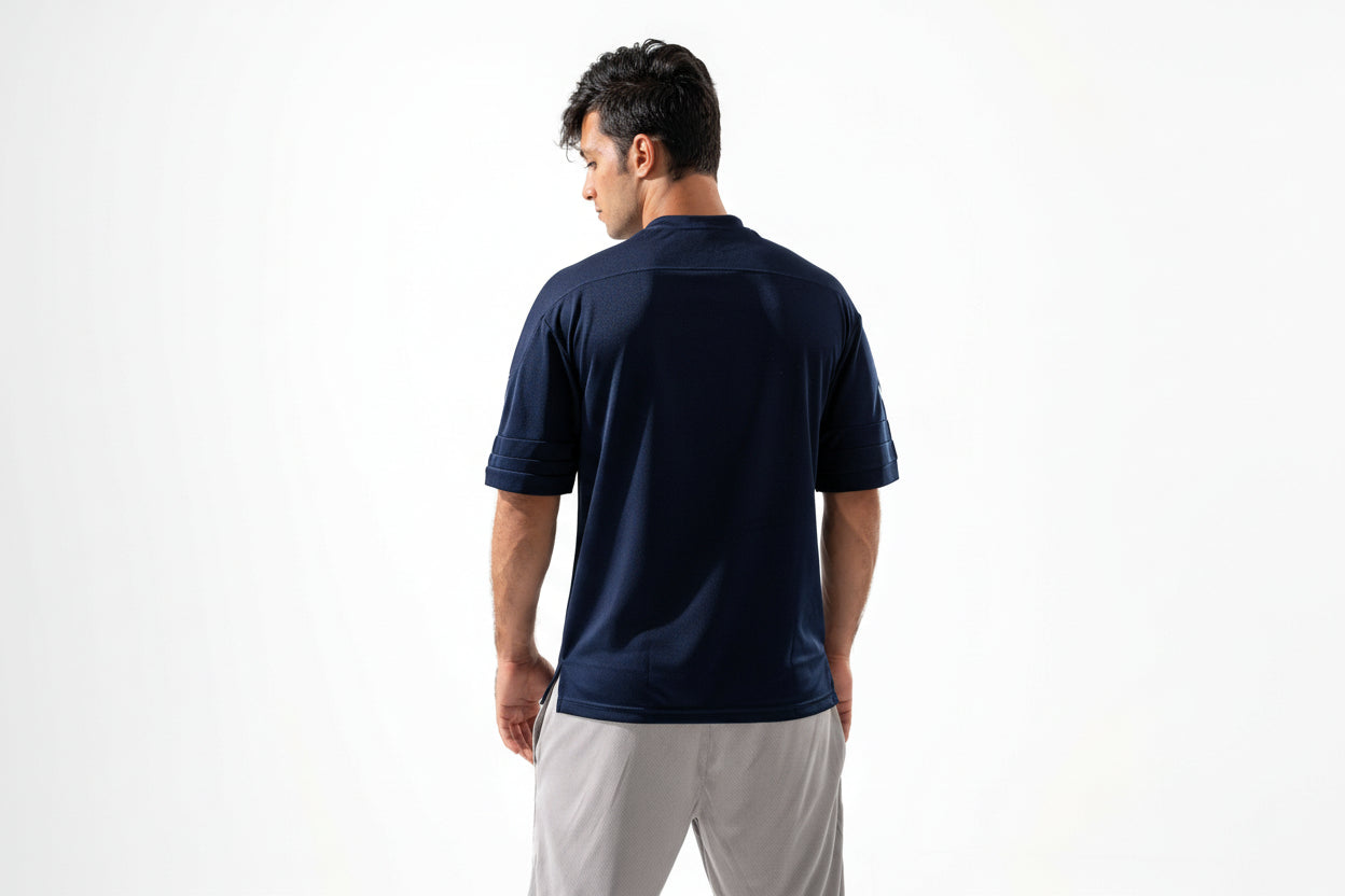 Man wearing a navy blue shirt and light gray shorts on a white background