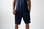 Person wearing navy athletic shorts and tank top on a white background