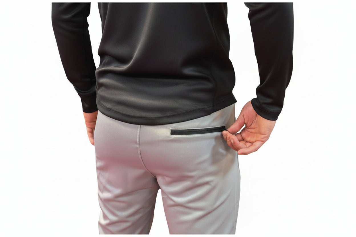 Person wearing a black top and light gray pants with a zipper on a dark background

