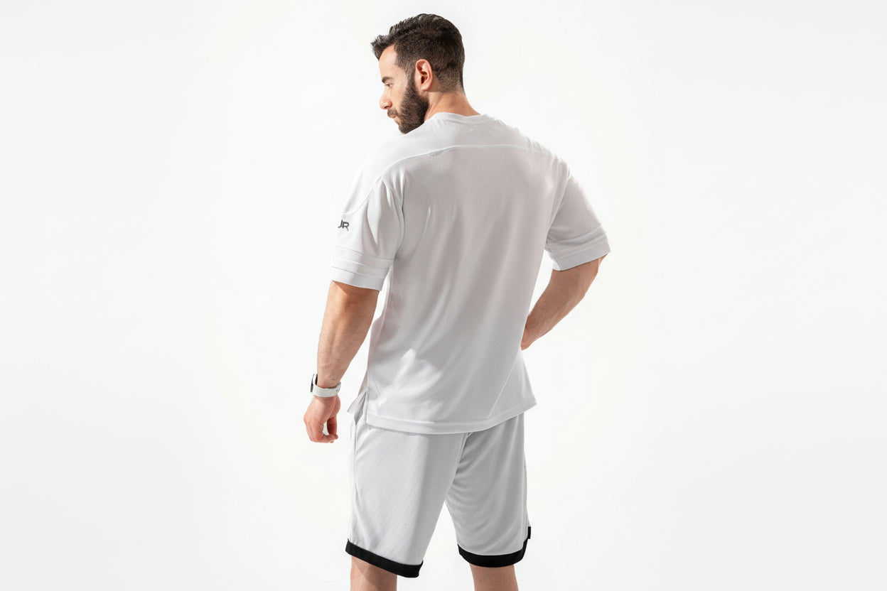 Man wearing a white sports outfit with a visible brand logo on a white background
