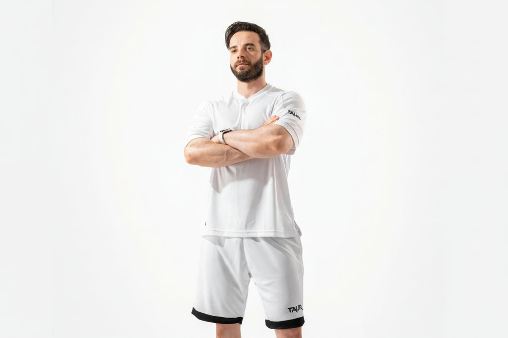 Man wearing a white polo shirt and shorts with a brand logo on a white background