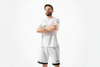 Man wearing a white polo shirt and shorts with a brand logo on a white background