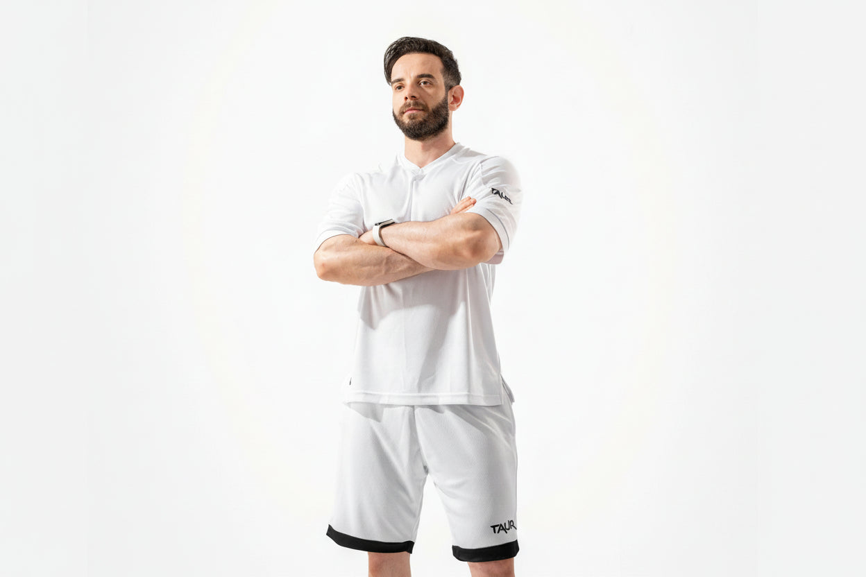 Man wearing a white polo shirt and shorts with a brand logo on a white background