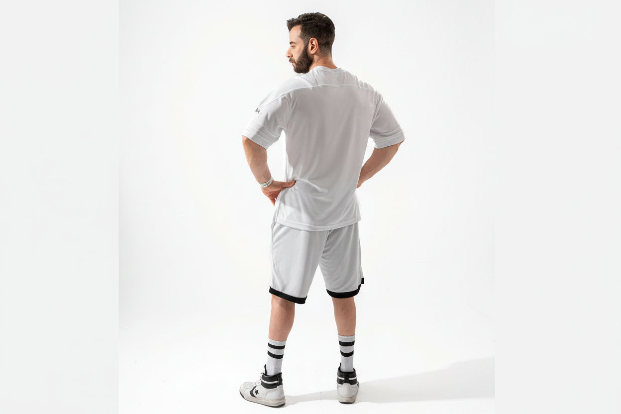 Man wearing a white sports outfit with black accents on a white background
