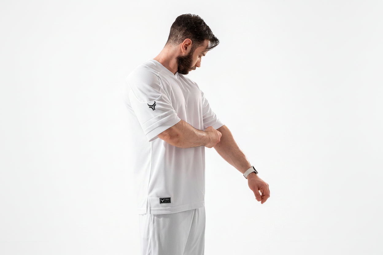 Man wearing a white sports outfit with a logo on a white background