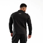 Man wearing a black tracksuit with 'Taur' branding on the back against a white background
